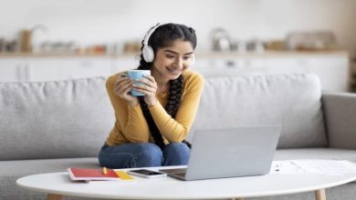 Woman wearing headphones and happily looking at a video on her laptop